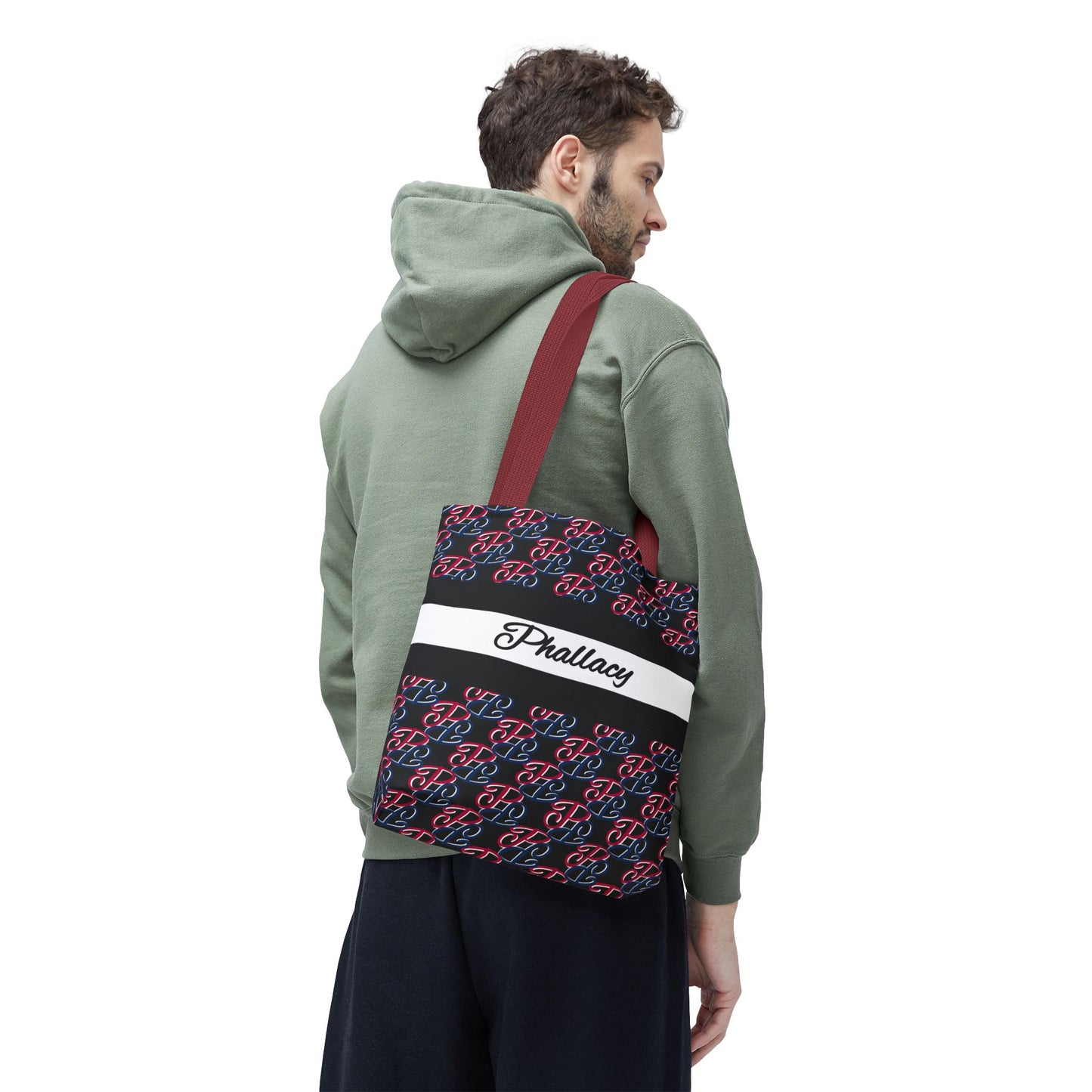 Man wearing green hoodie carrying Phallacy branded designer tote bag with red straps and monogram pattern