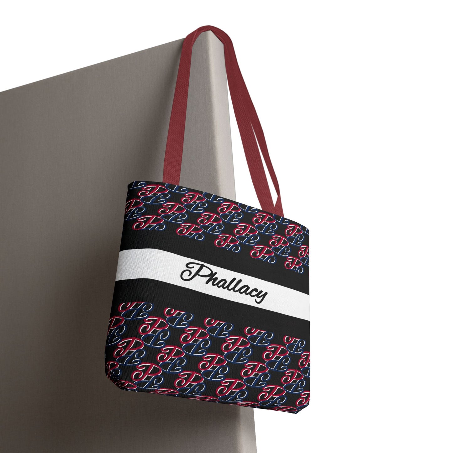 Phallacy designer tote bag with black, red, and blue pattern and red straps hanging on corner