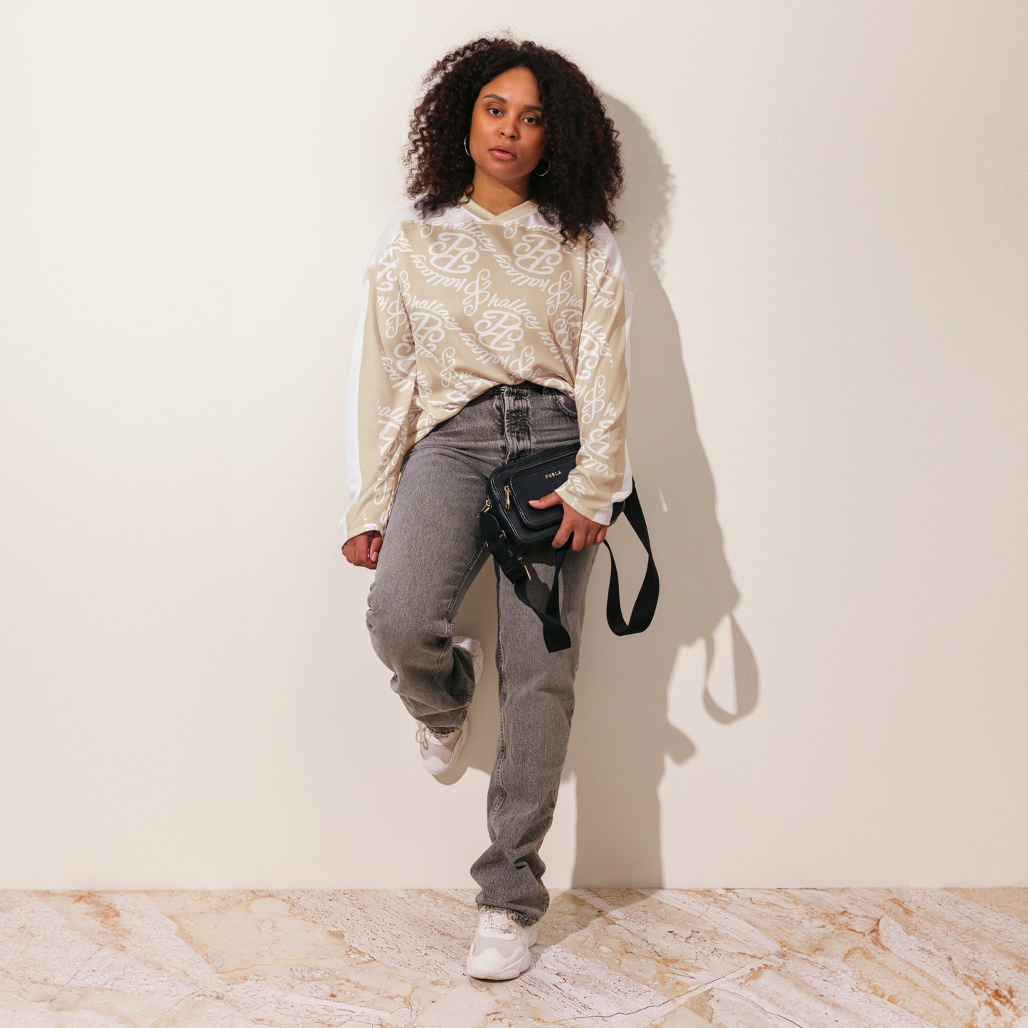 Stylish designer hockey jersey in beige with all over print, paired with casual jeans and a crossbody bag
