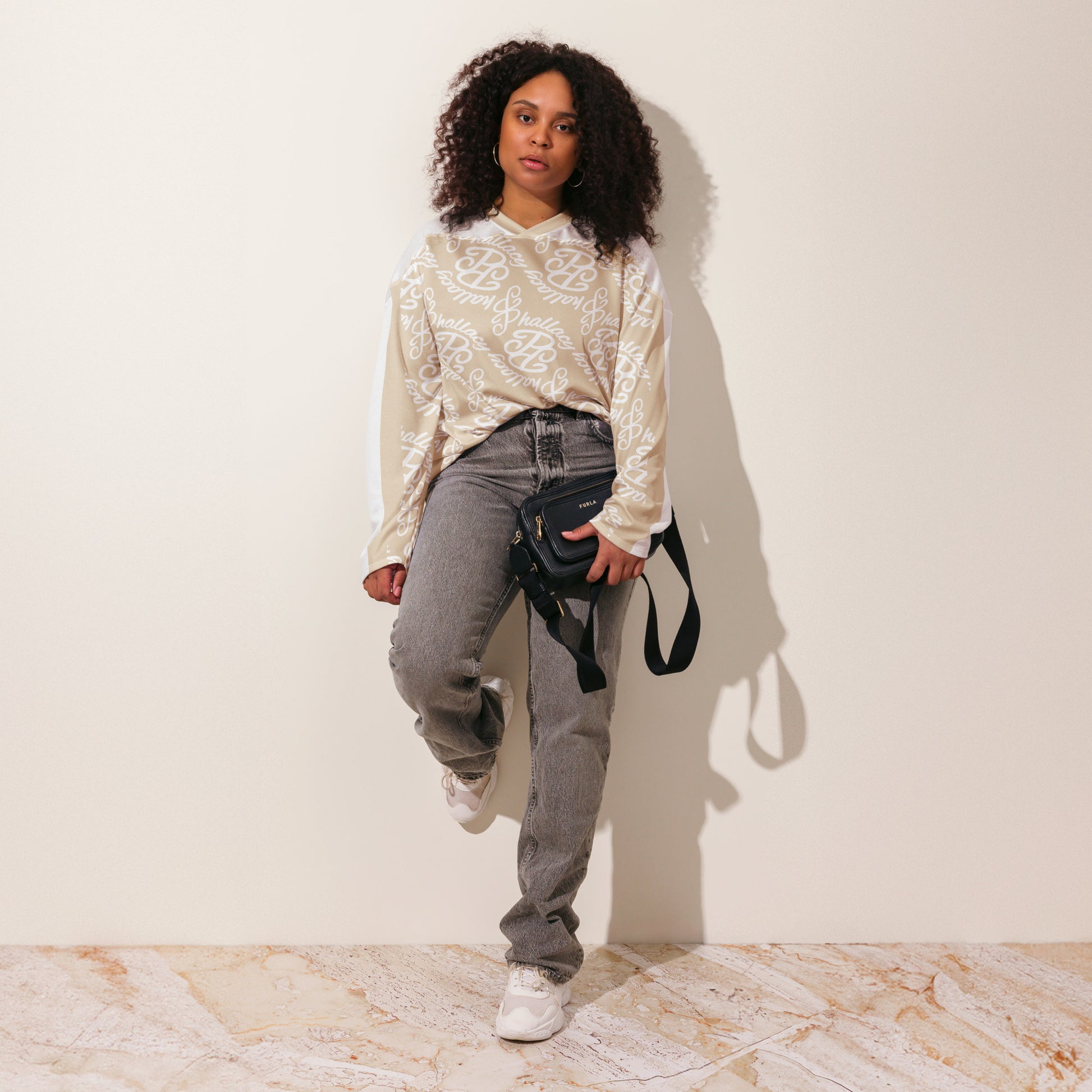 Stylish designer hockey jersey in beige with all over print, paired with casual jeans and a crossbody bag
