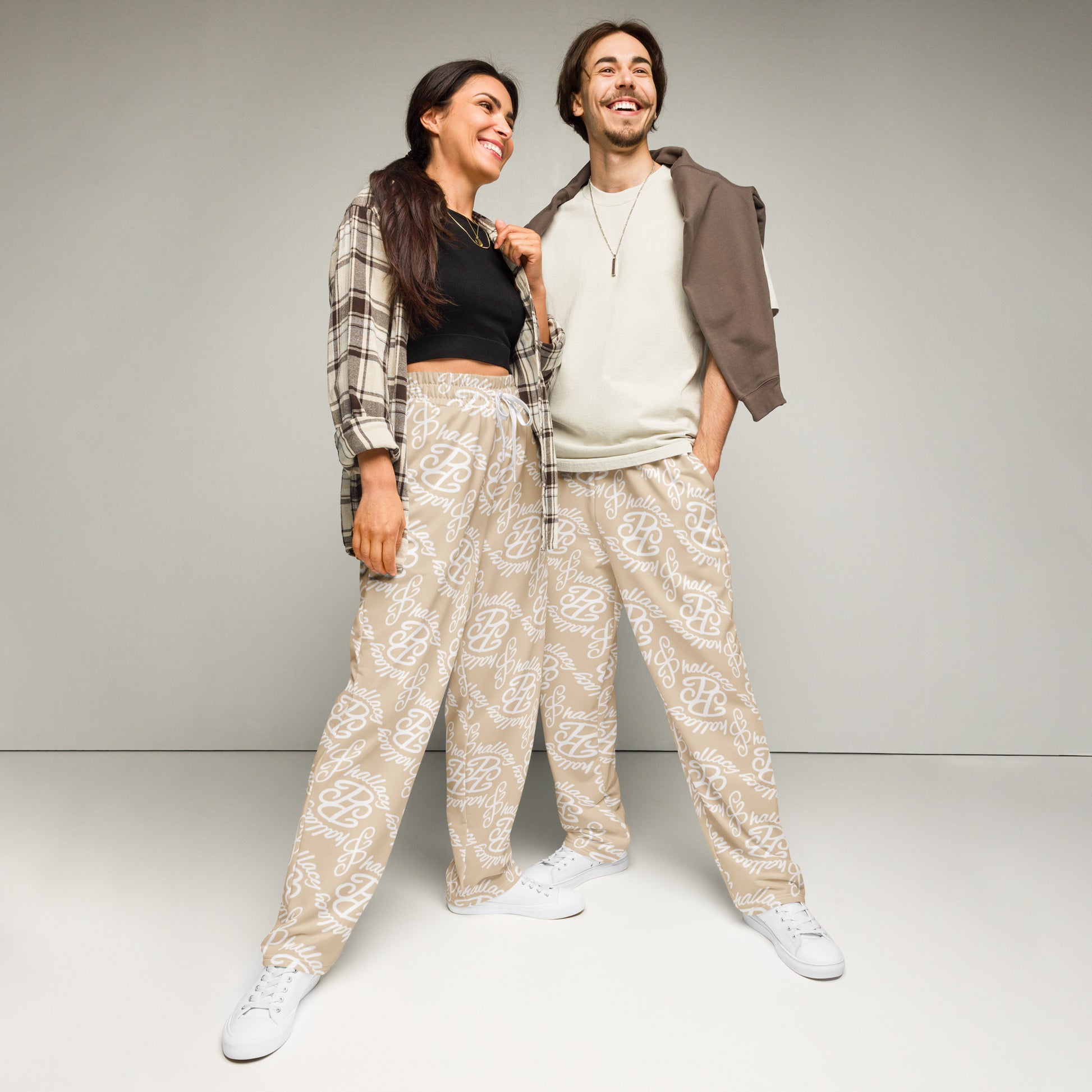 Stylish model duo wearing designer monogram wide-leg joggers in beige with a trendy print